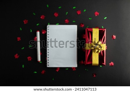 top view photo of notebook, writing in spiral notepad letter to santa and surprise box on isolated black background with copyspace. Concept happy new year, merry Christmas, valentines day

