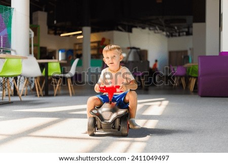 Young Child Riding Toy Car in Play Area Royalty-Free Stock Photo #2411049497