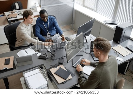 High angle shot of busy IT professionals sitting at office desks while developing cybersecurity protocols during workday in modern IT company Royalty-Free Stock Photo #2411056353