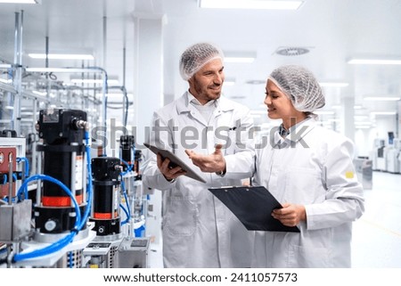 Experienced factory engineers discussing about productivity and efficiency in industrial building. Royalty-Free Stock Photo #2411057573