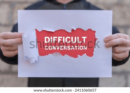 Man holding white and red sheets of paper with text: DIFFICULT CONVERSATION. Difficult conversation concept. Serious talk in sensible subjects at work or relationship, discuss personal issues conflict Royalty-Free Stock Photo #2411060657
