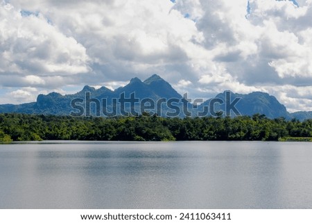 Kiew Kho Ma Dam with big mountain and forest, Wide lake with blue sky and white puffy clouds background, Located on Ban Huai Sanao Village, Pong Don, Chae Hom District, Lampang, Northern of Thailand. Royalty-Free Stock Photo #2411063411