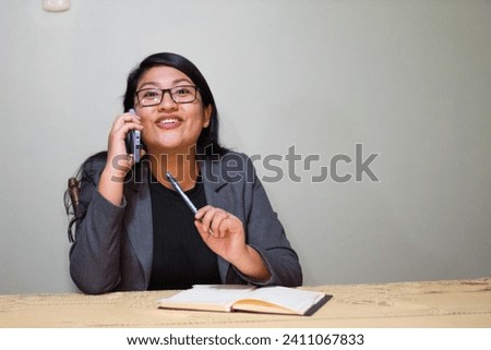 Caucasian woman in gray jacket sitting near the table talking on the phone with thoughtful face.