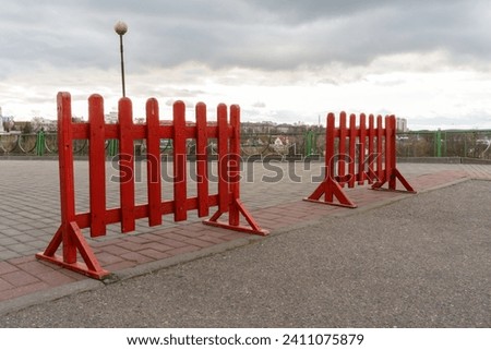 A portable red barrier for blocking dangerous territory on the sidewalk for work or maintenance personnel. A closed section of the sidewalk during construction work.