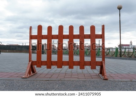 A portable red barrier for blocking dangerous territory on the sidewalk for work or maintenance personnel. A closed section of the sidewalk during construction work.