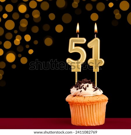 Number 51 birthday candle - Cupcake on black background with out of focus lights Royalty-Free Stock Photo #2411082769