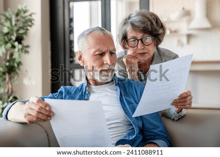 Senior old elderly spouses grandparents reading documents, having issue problem debt with money loss, doing paperwork together at home. Mortgage, loan and commerce procedures Royalty-Free Stock Photo #2411088911