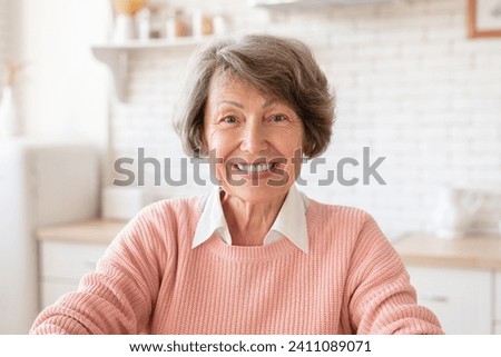 Closeup cropped portrait of senior old elderly caucasian woman grandmother housewife looking at camera with toothy smile at home kitchen. Videocall concept Royalty-Free Stock Photo #2411089071