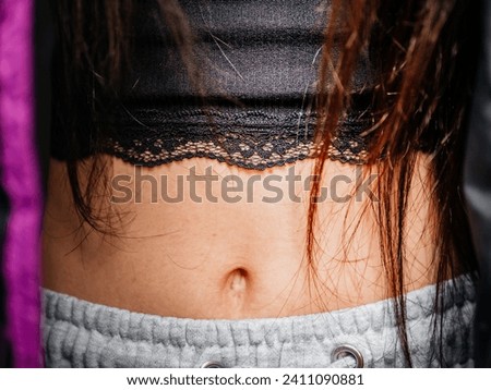 Woman slim stomach with belly button and short black T shirt. Model with long red brown hair. Beauty and fashion. Popular teenager trend. Royalty-Free Stock Photo #2411090881