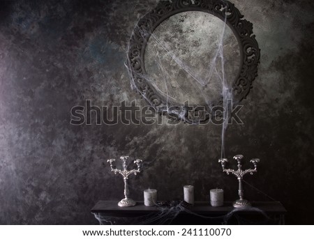 Decorative Round Frame Above Candles and Candelabras on Eerie Cobweb Covered Mantle in Haunted House Setting