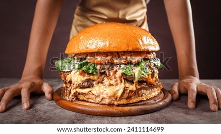 Giant homemade wagyu beef burger on wooden plate. Royalty-Free Stock Photo #2411114699