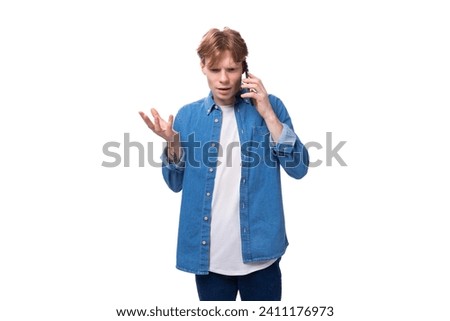 portrait of a successful business caucasian red-haired guy in a denim blue shirt with a phone in his hand