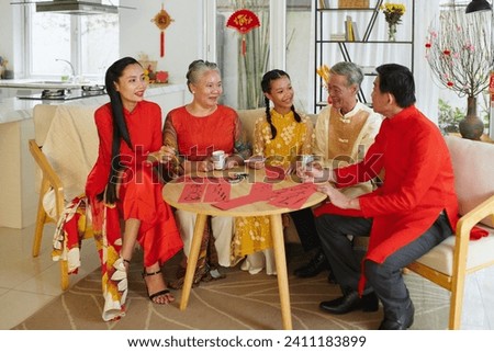 Positive big Vietnamese family practicing calligraphy together when gathered at home to celebrate Tet Royalty-Free Stock Photo #2411183899