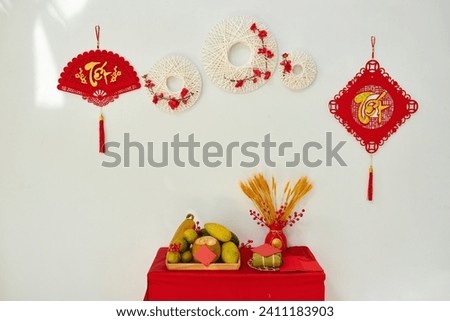 Vietnamese lunar new year decorations with ornaments hanging on wall and table with fresh fruits Royalty-Free Stock Photo #2411183903