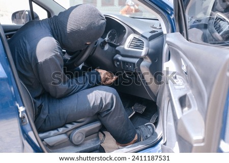 Car thief trying to start car with screwdriver in ignition. Royalty-Free Stock Photo #2411187531