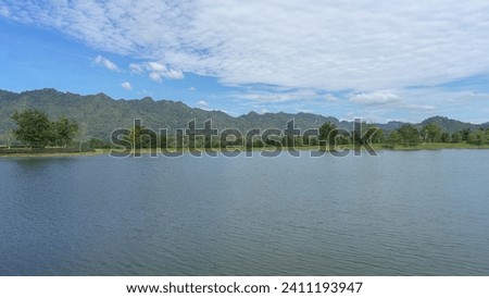 The pond is as wide as the eye can see. It is large in the park. In the background, you can see the mountains. And there is a picture of a transparent sky reflecting water. rough water surface Streaks
