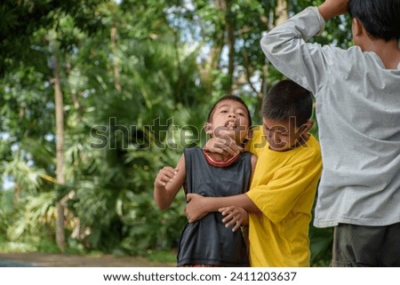 Group of children were fighting and physically attacking each other due to childhood bullying and school violence at outdoor park in forest blurred background. Royalty-Free Stock Photo #2411203637