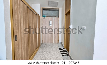 Hotel room entrance with built-in cabinets and wooden doors. Long and narrow corridor against of doors and cabinet, passing through the entire hallway. Corridor with closet in hotel room.