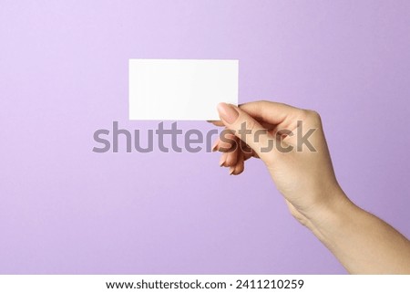 Woman holding blank business card on violet background, closeup. Mockup for design Royalty-Free Stock Photo #2411210259