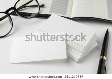 Blank business cards, glasses and pen on white table. Mockup for design