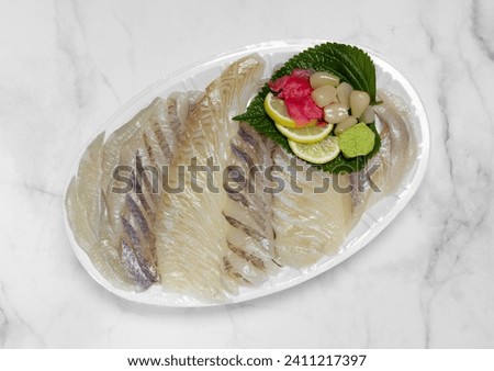 Sashimi in plastic container isolated on white marble background. Delivery or takeout sea food. Sliced raw flatfish and raw rockfish. Top view.
