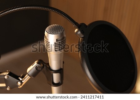 Stand with microphone and pop filter on blurred background, closeup. Sound recording and reinforcement