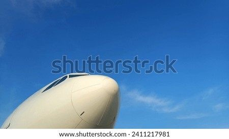 White airplane's nose radome under blue sky in the morning, view from below