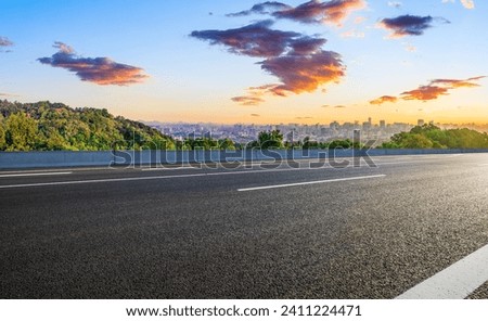 Asphalt road and green mountains with city skyline landscape at sunrise. high angle view.