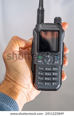 amateur radio walkie talkie portable triband held in the hand of a white man Royalty-Free Stock Photo #2411225849