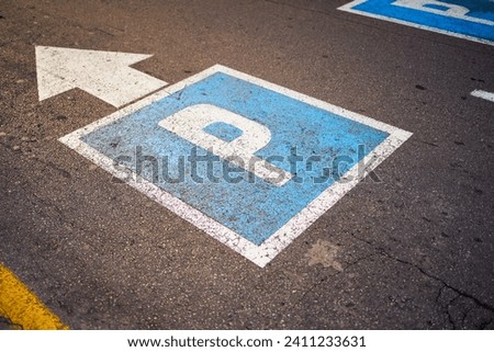 Blue parking sign on asphalt with directional arrow.