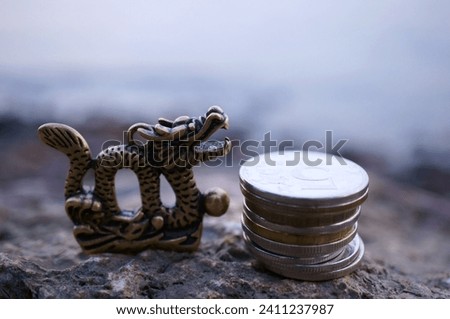 A Chinese dragon figurine and a stack of coins.