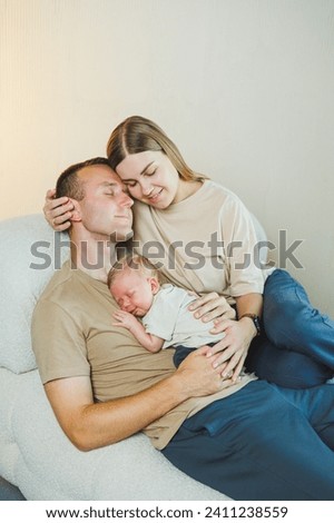 Happy young family with a newborn baby. Beautiful mother and father kissing their child. Parents and smiling child in arms, isolated over white background.