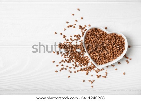 Raw buckwheat in a bowl on a textured wooden background. Wheat grains, porridge, cereals, raw buckwheat in a plate. Healthy food. Porridge. Diet. Organic cerea. Space for text.Copy space.