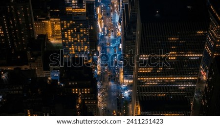 Night Aerial Photo of New York City with Skyscraper Spires and Straight Busy Streets with Cars and Yellow Taxi Vehicles. Top Down Helicopter View of Office Buildings in a Big Urban Center