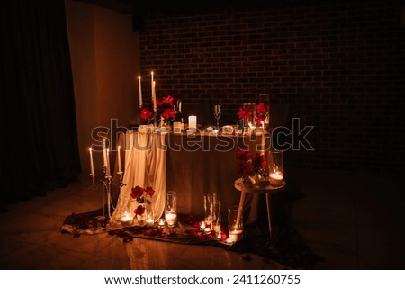 Location for a surprise proposal at night. Decoration flowers, burning candles. Luxury romantic date. Table setting in restaurant for event. Candlelight for couple on Valentines day. Royalty-Free Stock Photo #2411260755