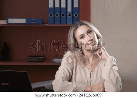 Female emotional portrait in the office. The woman looks at the camera and smiles thoughtfully. Close-up.