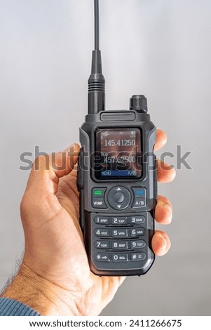 amateur radio walkie talkie portable triband held in the hand of a white man Royalty-Free Stock Photo #2411266675