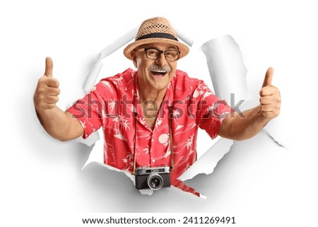 Mature male tourist peeking through a paper hole and gesturing thumbs up isolated on white background