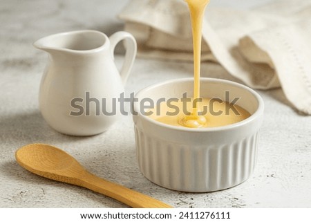 Fresh condensed milk in the bowl. Royalty-Free Stock Photo #2411276111
