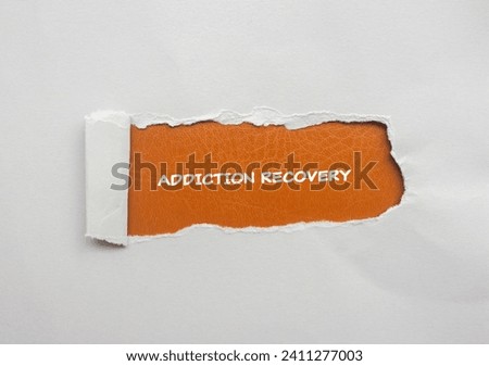 Addiction recovery lettering on ripped gray paper with brown background. Conceptual photo. Top view, copy space.
