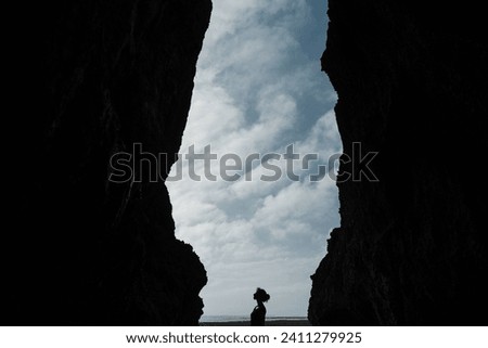 Outline of a girl posing against the backdrop of the ocean among the rocks