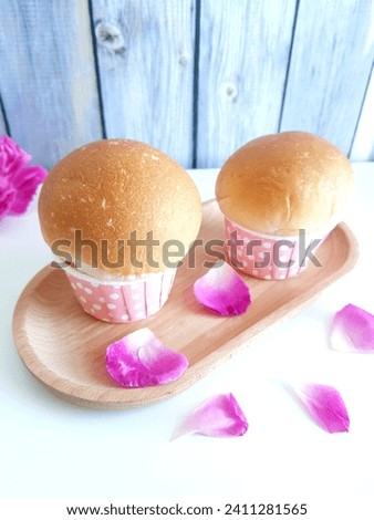 A pair cups of bread on awooden tray decorated with rose petals