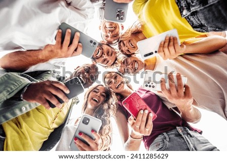Teens in circle holding smart mobile phones - Multicultural young people using cellphones outside - Teenagers addicted to new technology concept Royalty-Free Stock Photo #2411285629