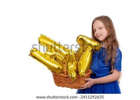 Little girl in a festive blue dress holds a golden set of happy birthday inflatable letters. Isolated on a white background.