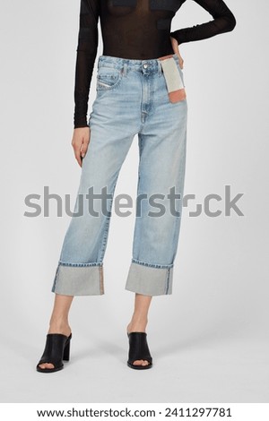 Women's cuff cropped jeans on model isolated on white background. Woman wearing light blue denim wide jeans, heels, autumn spring outfit. Template, mock up, jeans fashion concept