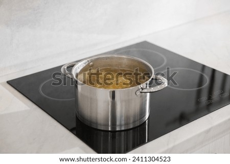 Pot with delicious soup on cooktop in kitchen Royalty-Free Stock Photo #2411304523
