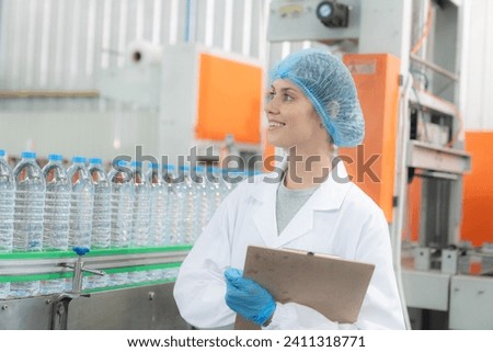 Young happy woman worker in factory checking water gallons before shipment.