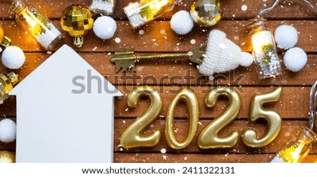 House key with tiny figure of home mock up on festive brown wooden background, lights of garlands. New Year 2025 wooden letters, greeting card. Purchase, construction, relocation, mortgage, insurance