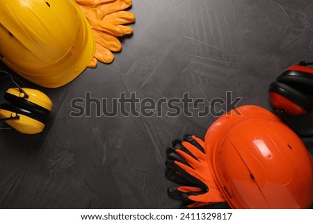 Hard hats, gloves and earmuffs on grey table, flat lay with space for text. Safety equipment Royalty-Free Stock Photo #2411329817
