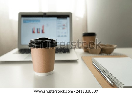 a glass of coffee on the background of a laptop with charts on a white table.